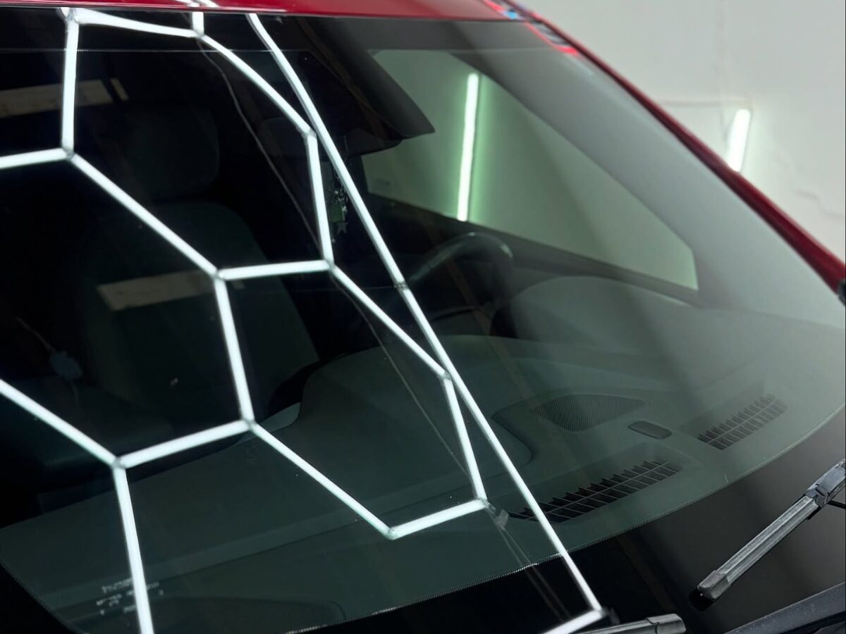 Geometric light reflection on red car windshield surface | Icon Auto Lab