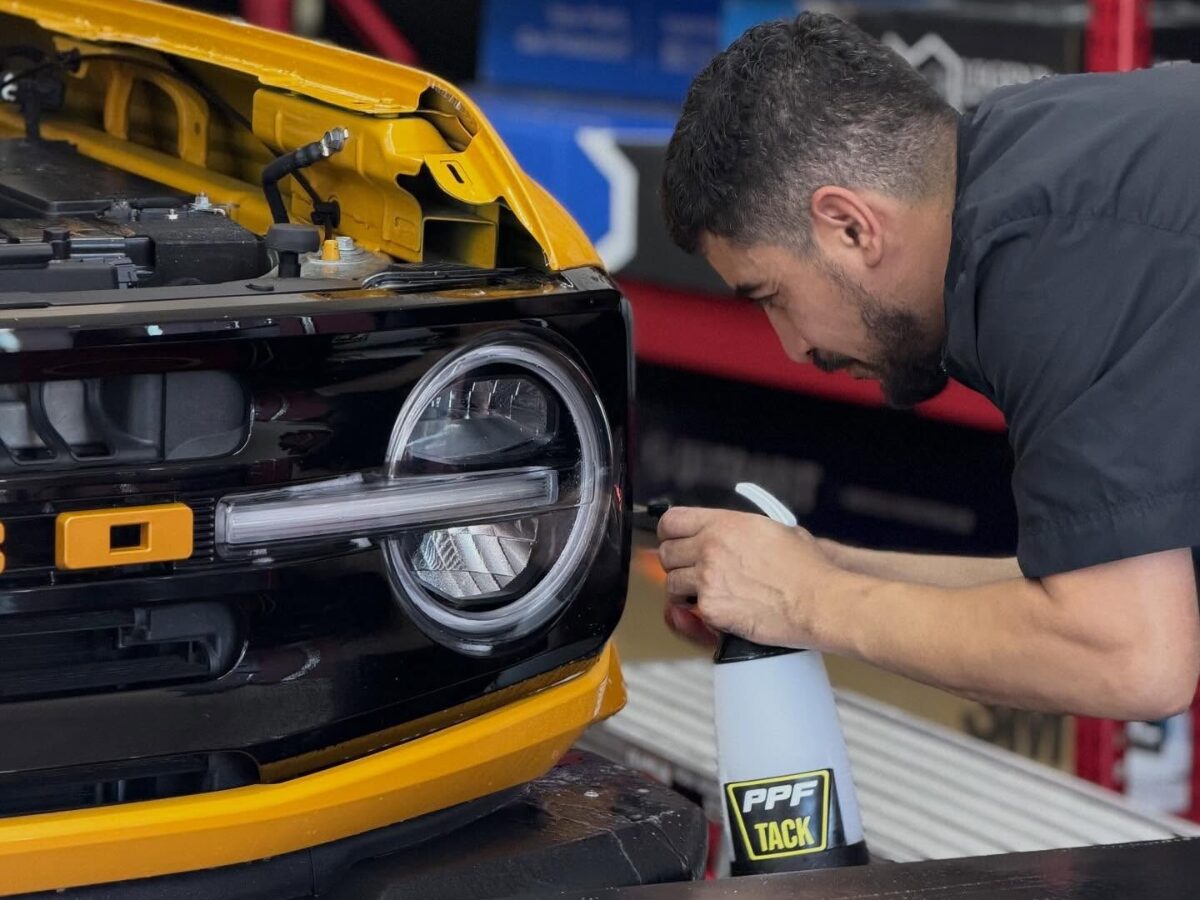Applying PPF tack spray near headlight on black-yellow car | Icon Auto Lab
